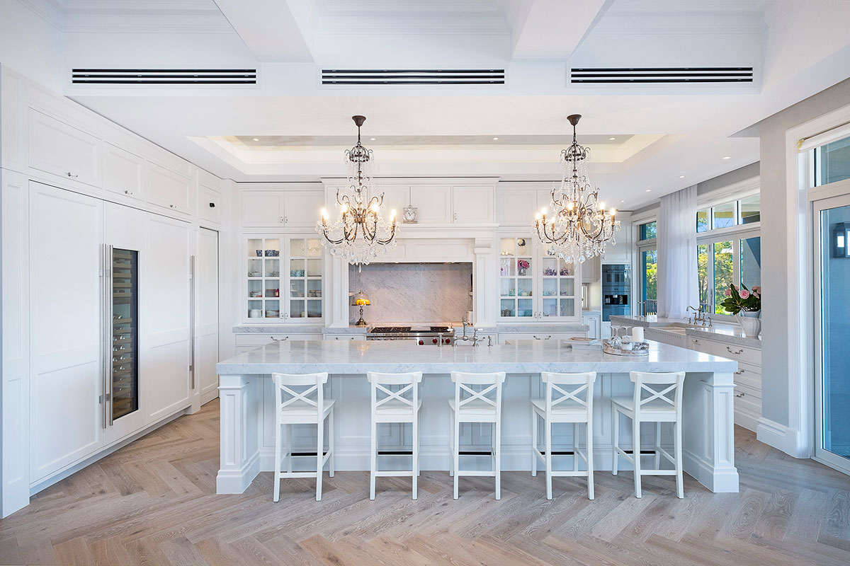 A kitchen with white cabinets and a chandelier, creating a bright and elegant space for cooking and dining.