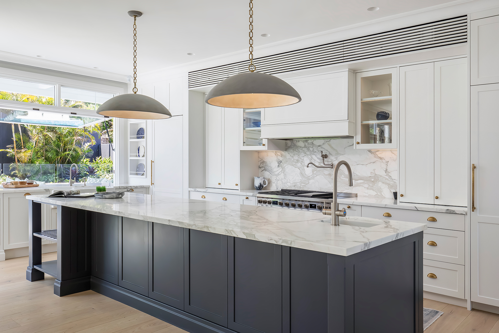 Modern kitchen with marble island, pendant lights, and white cabinetry for a sleek look.